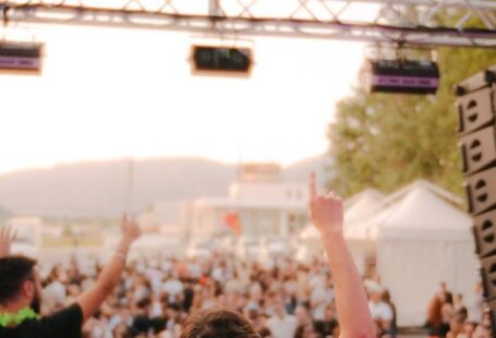Summer Festivals - Back View of Men Playing Music on Stage and the Audience Having Fun at a Festival
