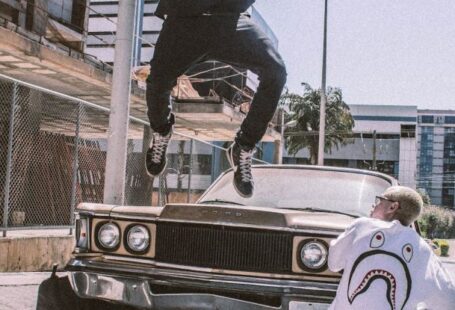 Street Fashion - Man Jumping on Front of Brown Car