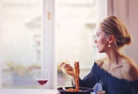 Italian Elegance - Woman Sitting on Chair While Eating Pasta Dish